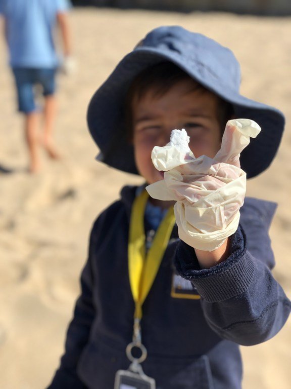 Children cleaning Praia da Poça, a small and popular beach at the beginning of the Estoril - Cascais coast, in Portugal.